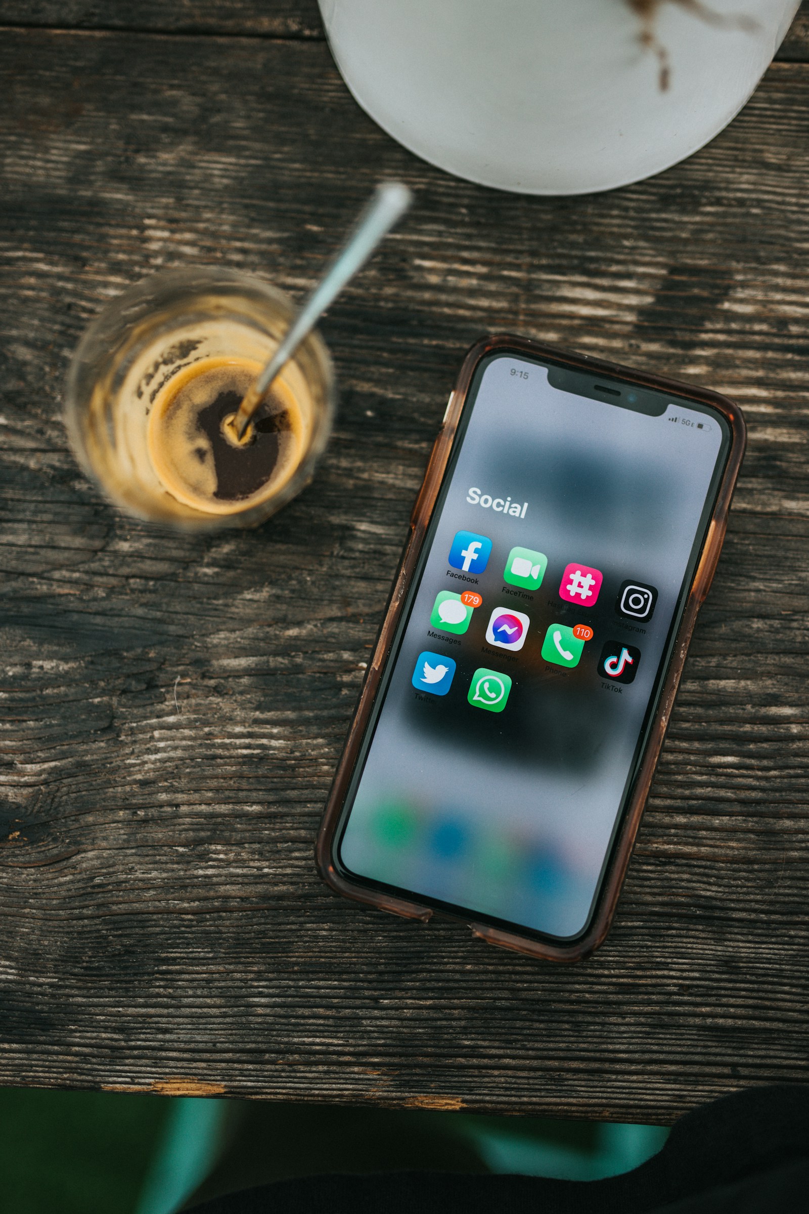 Smartphone displaying social media apps beside a cup of coffee